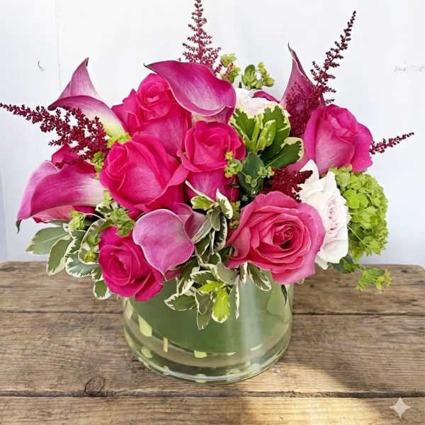 Pink roses and calla lilies arranged in a glass vase