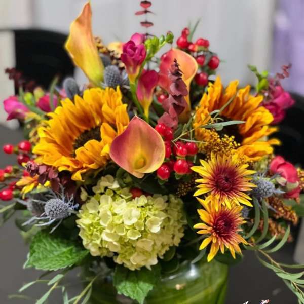 Colorful bouquet with sunflowers, calla lilies, and hydrangea in a green vase