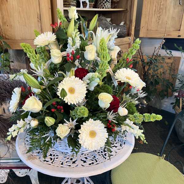 Large white floral arrangement with daisies, roses, and lilies in a decorative bowl