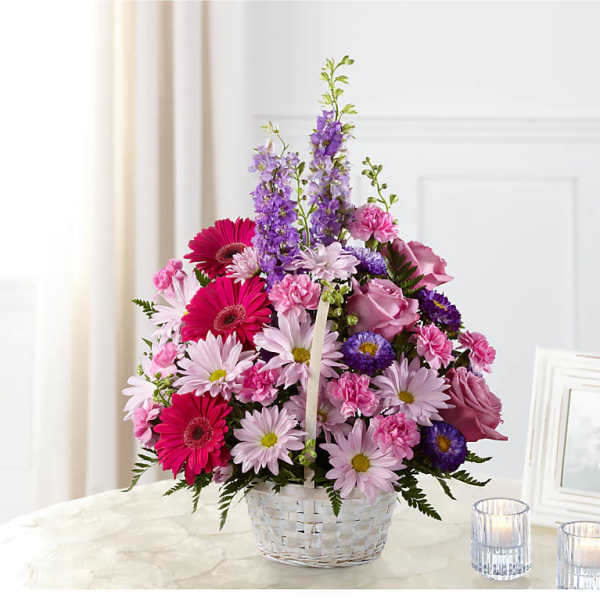 Pink and purple mixed flowers arranged in a white basket