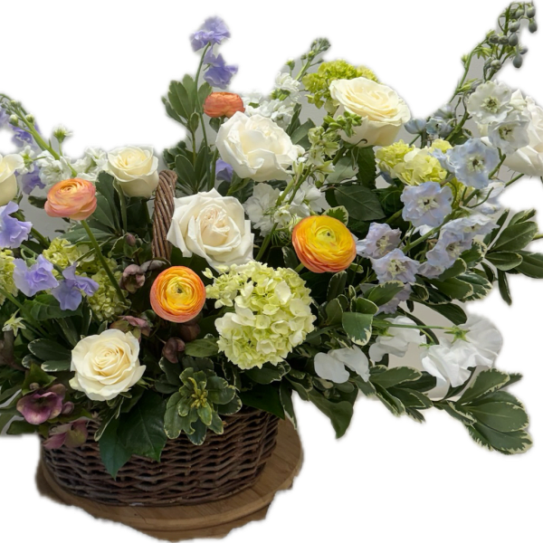 Basket arrangement of white roses, ranunculus, and pastel blue flowers