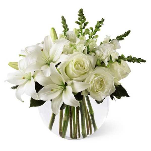 White lilies and roses arranged in a clear glass vase