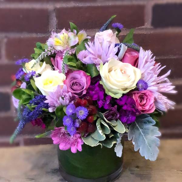 Mixed bouquet of roses and purple flowers in a green vase