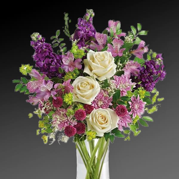 Bouquet of white roses, purple flowers, and pink blooms in a clear vase