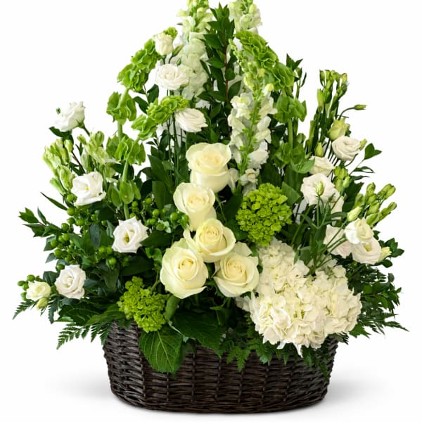 White roses and green flowers arranged in a wicker basket
