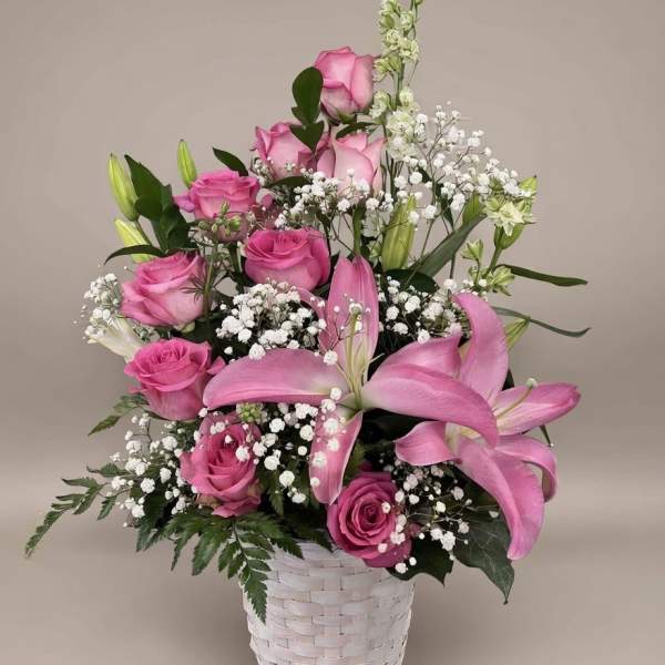 Pink roses and lilies arranged in a white basket