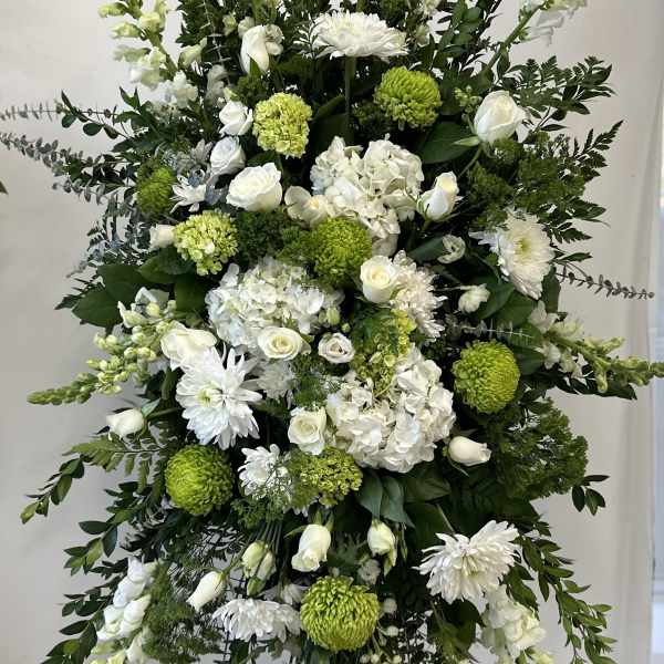 Tall white and green funeral spray on a stand