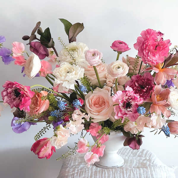 Pastel floral arrangement in a white vase with pink, purple, and white blooms