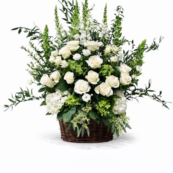 White rose arrangement in a wicker basket with tall greenery
