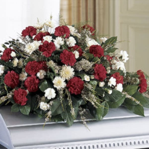 Red and white carnation casket spray with greenery