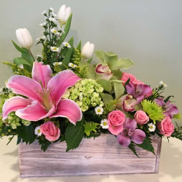 Pink lilies and roses in a wooden box with mixed blooms
