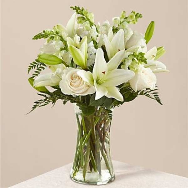 White lilies and roses arranged in a clear glass vase