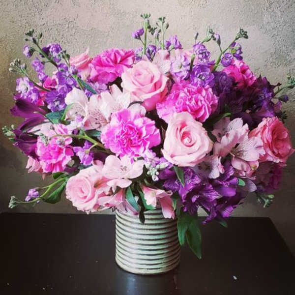 Pink and purple mixed flower arrangement in a striped vase