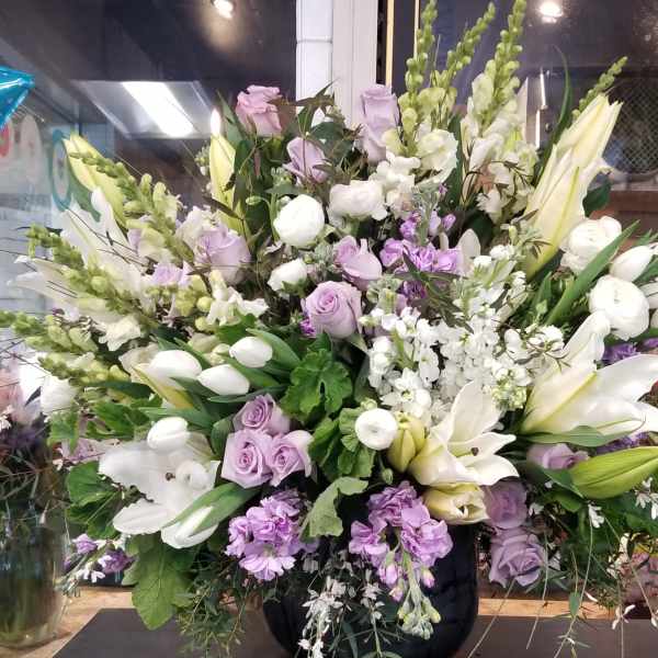 Large lavender and white floral arrangement in a black vase