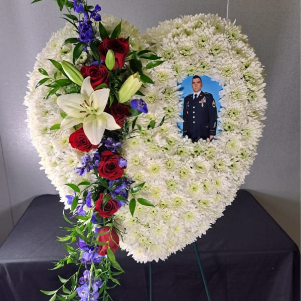 Heart-shaped funeral wreath with a photo inset and red roses