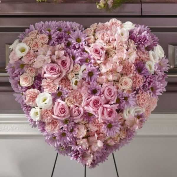 Heart-shaped floral arrangement with pink and lavender roses and daisies