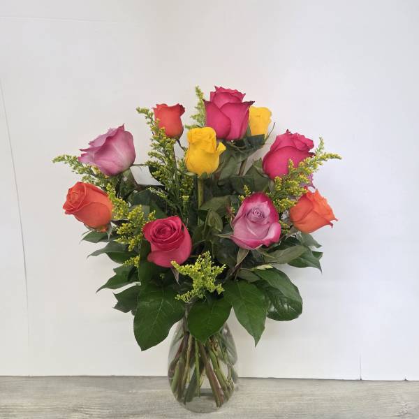 Glass vase of mixed pink, yellow, orange, and lavender roses with yellow filler flowers