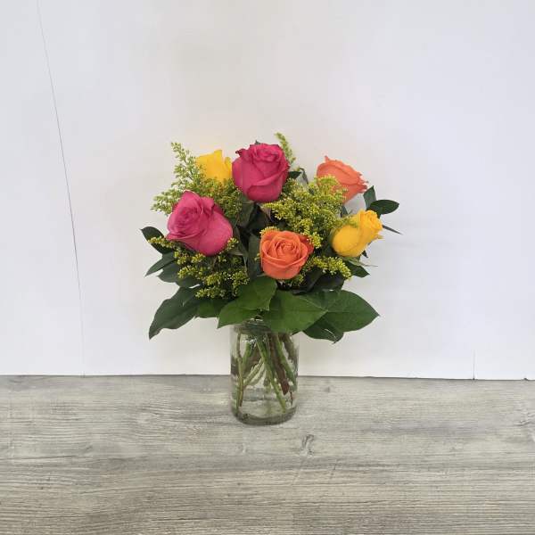 Bright bouquet of pink, yellow, and orange roses with yellow filler in a clear glass vase