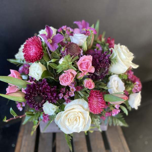 Mixed pink and white flower bouquet in a wooden crate