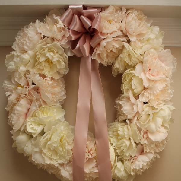 Cream floral wreath with a pink satin bow and long ribbon tails