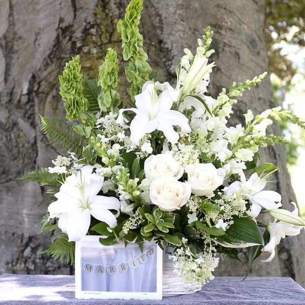 White lilies and roses in a basket with a "Married" sign