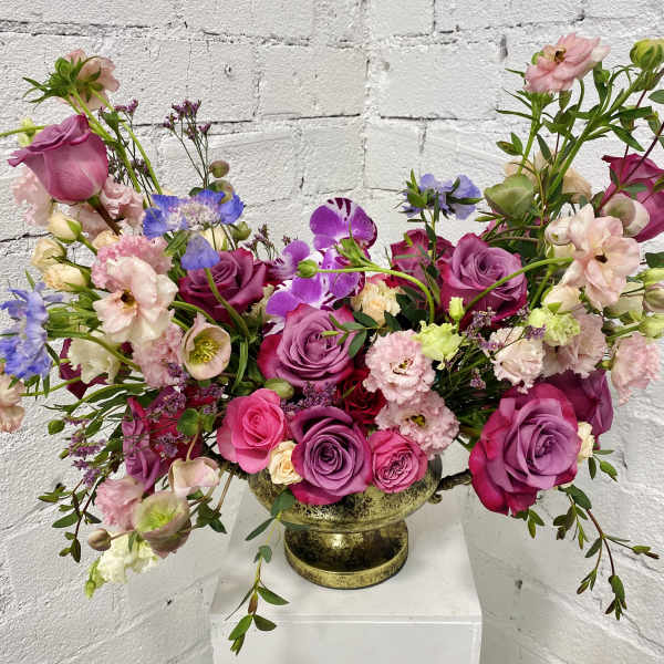 Mixed pink and purple floral arrangement in a gold vase