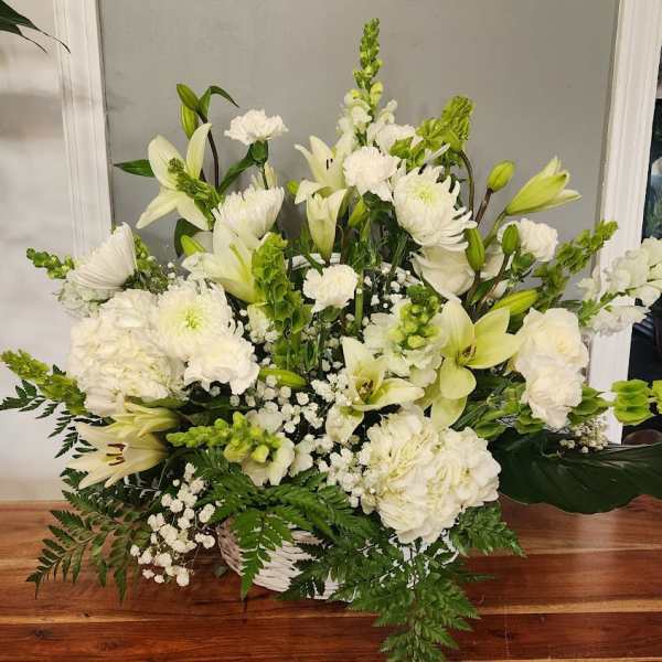 White floral arrangement with lilies, chrysanthemums, and carnations in a basket