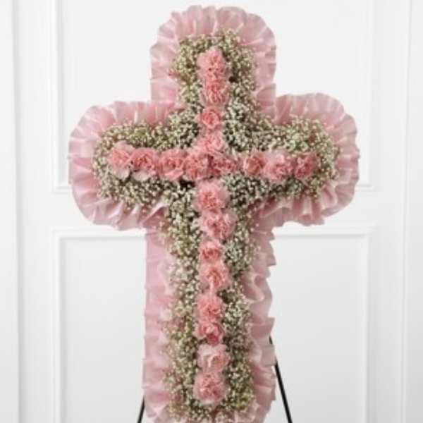 Pink floral cross on an easel with ruffled trim