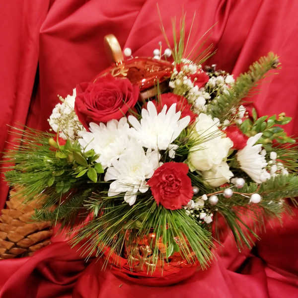 Red and white floral arrangement in a gold basket on red fabric