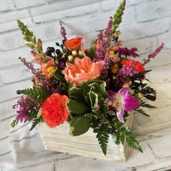 Mixed bouquet in a white wooden box with pink, orange, and purple flowers