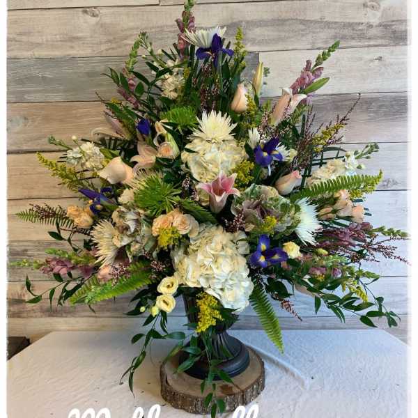 Large mixed floral arrangement in a black pedestal vase