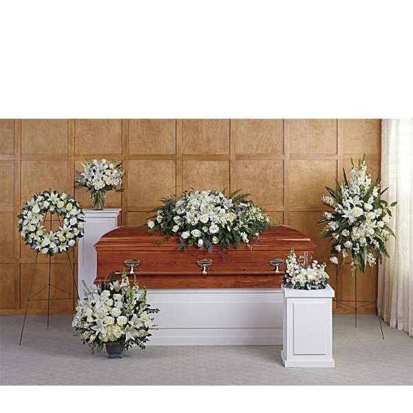 White funeral casket surrounded by white floral sprays and wreaths