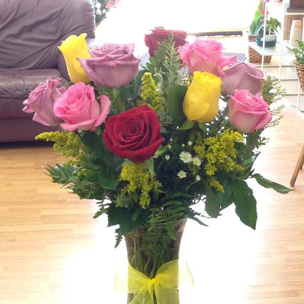 Bouquet of pink, red, and yellow roses in a clear glass vase