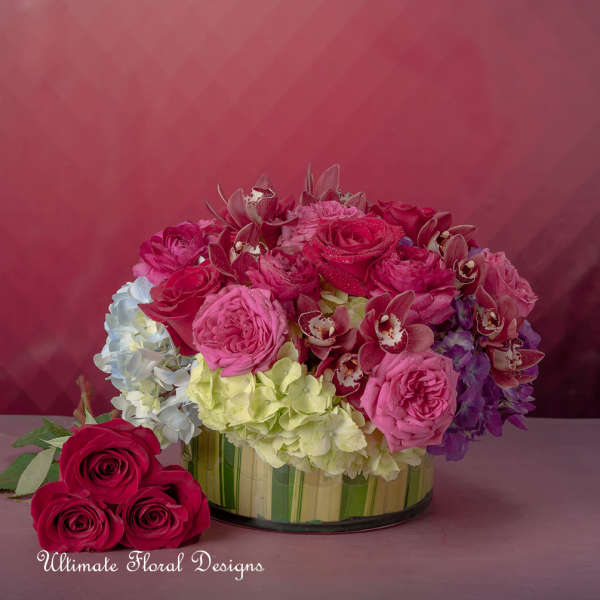 Pink and red roses with hydrangeas in a low glass vase