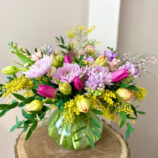 Mixed bouquet of pink and lavender flowers in a glass vase