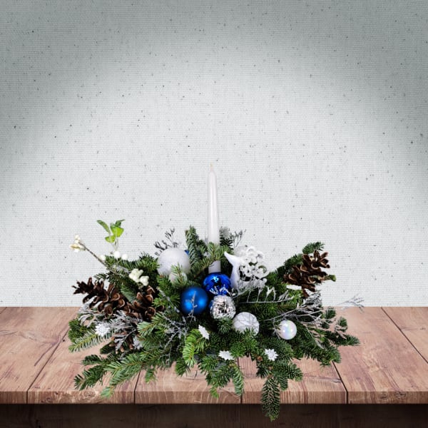 Holiday centerpiece with a white candle, pinecones, and blue ornaments