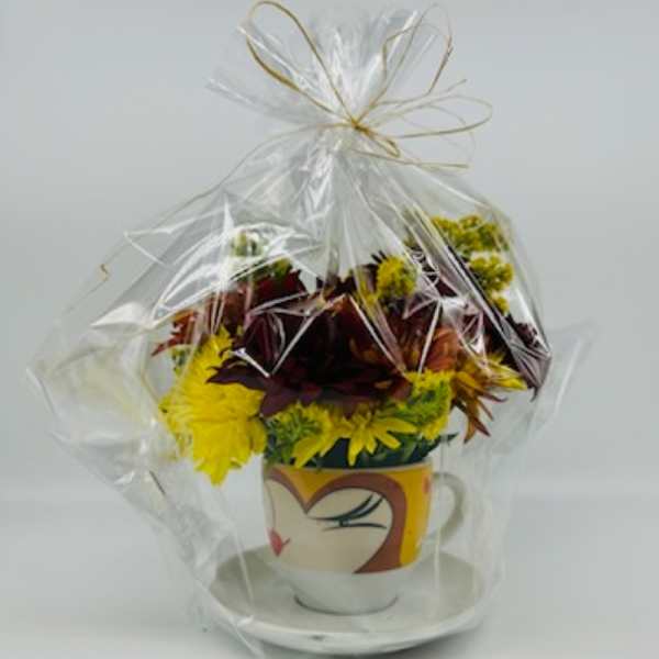 Bouquet of yellow and burgundy flowers in a decorative mug, wrapped in clear cellophane