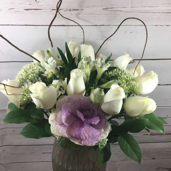 White roses and purple ornamental cabbage in a vase arrangement