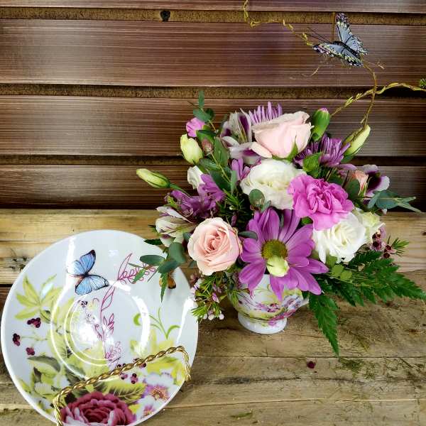 Bouquet of pink, white, and purple flowers in a decorative teacup vase