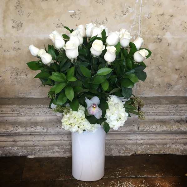 White roses and hydrangeas arranged in a tall white vase