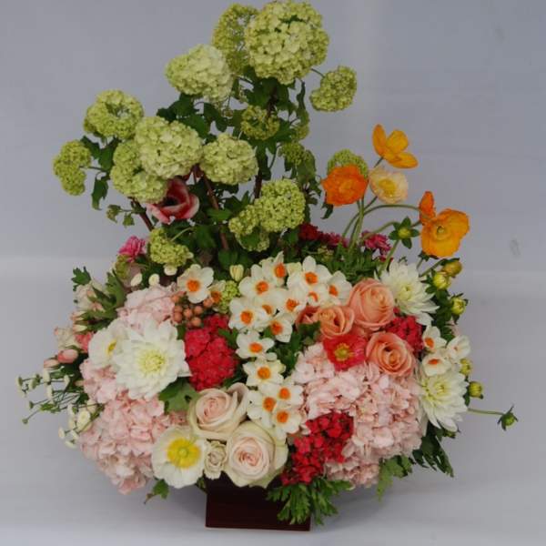 Large mixed floral arrangement with pale green blooms, pink roses, and white flowers