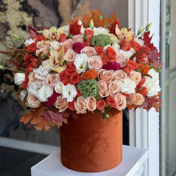 Large mixed bouquet of roses, orchids, and carnations in an orange velvet box