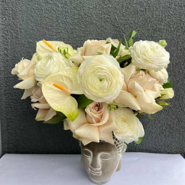 Cream bouquet with white calla lilies and roses in a sculpted face vase