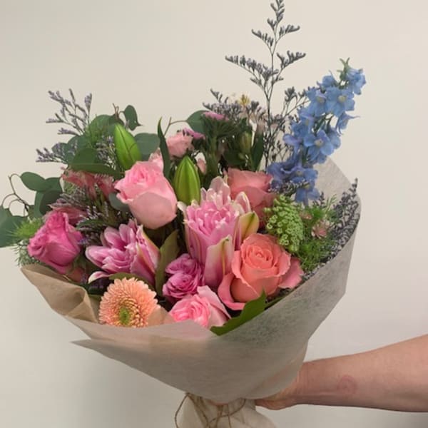 Hand-tied bouquet of pink and blue flowers wrapped in paper