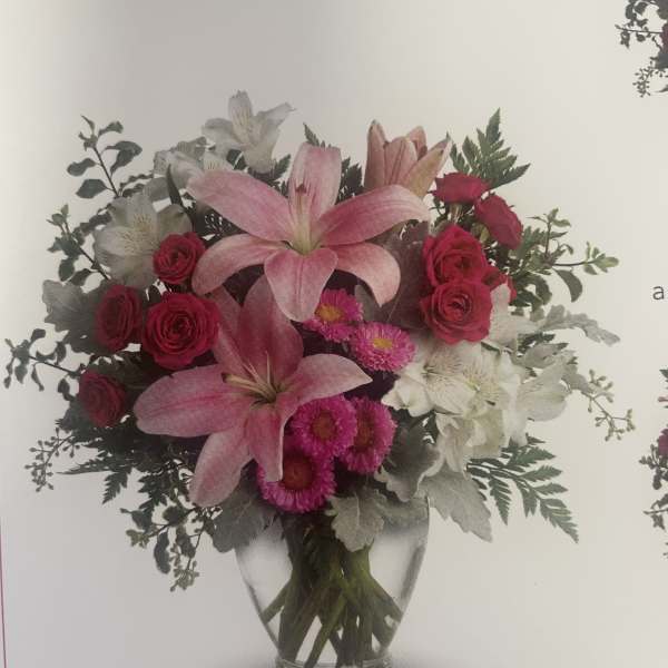 Pink lilies and roses arranged in a clear glass vase