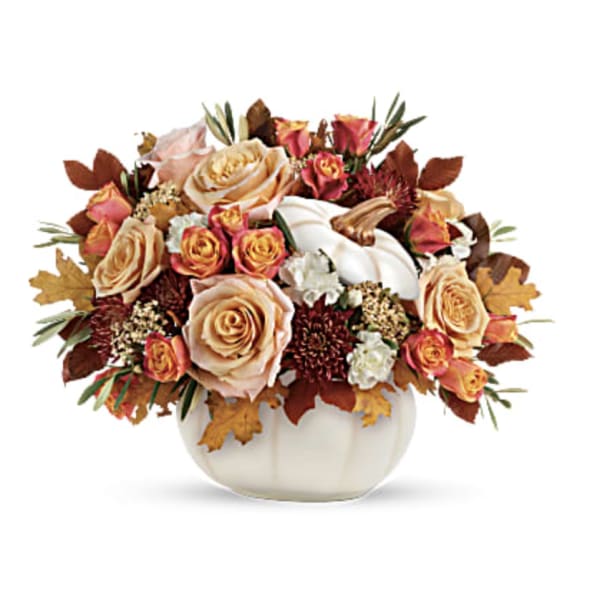 Autumn bouquet of peach and pink roses in a white pumpkin vase