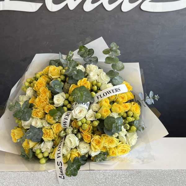 Bouquet of yellow and white roses with eucalyptus and berry accents