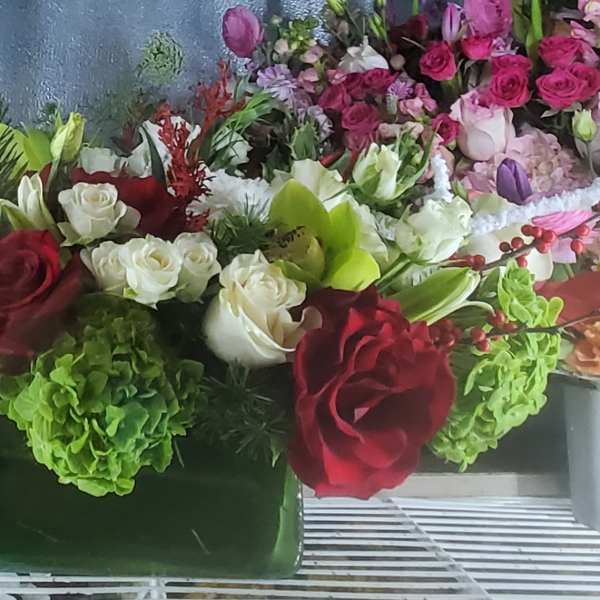 Mixed bouquet of red, white, and green flowers in a rectangular vase