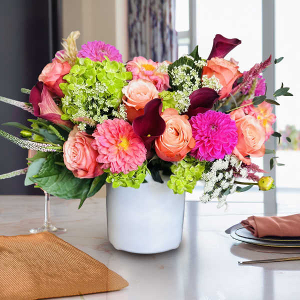 Mixed bouquet of pink and peach flowers in a white vase
