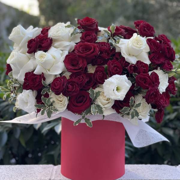 Red and white rose arrangement in a pink box